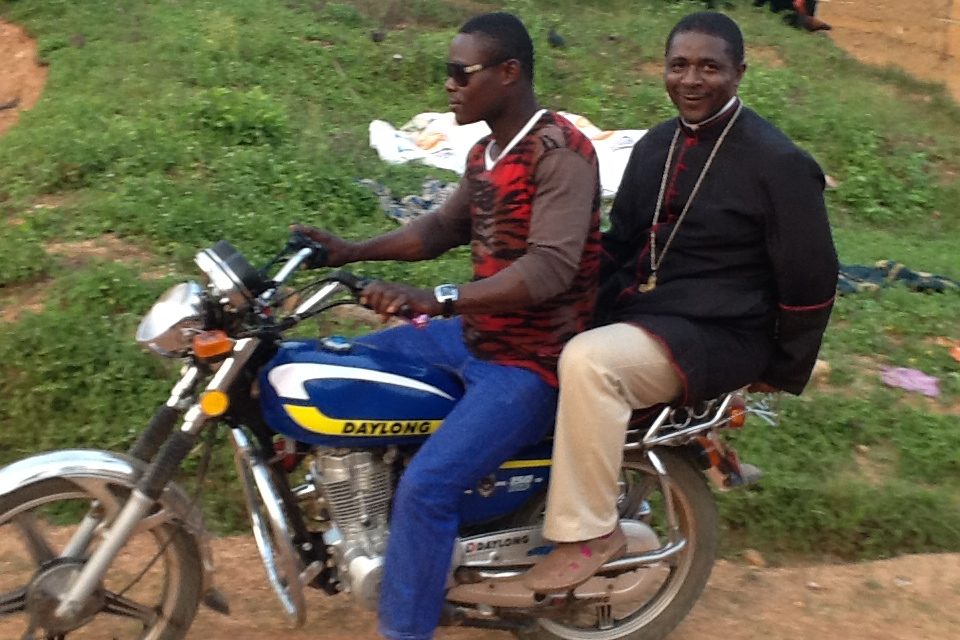 Bishop Andrew Nkea (right) on a motorcycle (©: ACN)