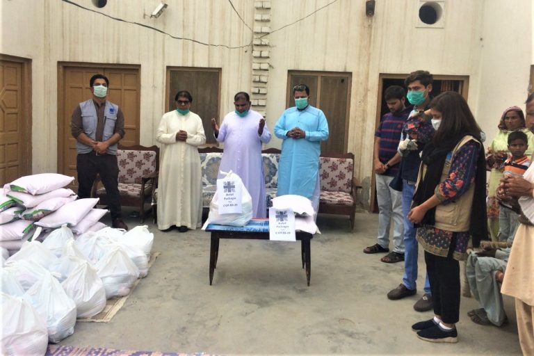 With picture of a priest blessing food for distribution to families in need (© Caritas Pakistan Faisalabad)