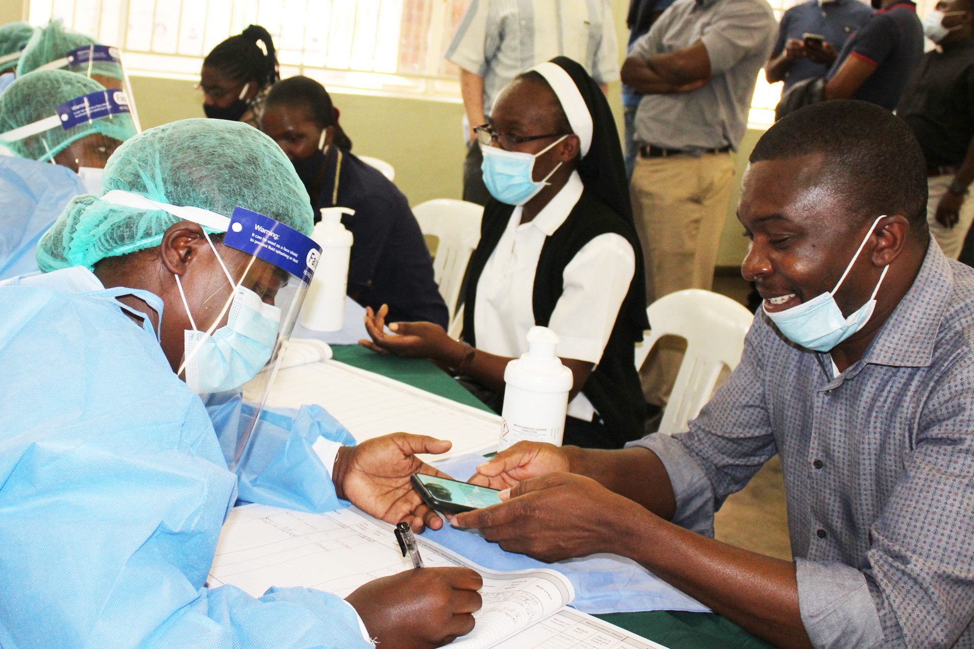 With image of clergy and Religious with staff dressed in PPE at a vaccination centre (© Aid to the Church in Need)