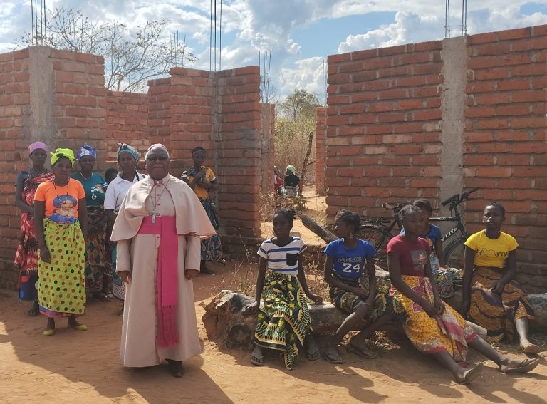 Bishop Atanasio Amisse Canira with parishioner roofing a church.